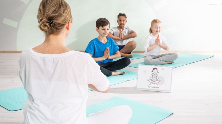 Kinderyogalehrerin mit Kindern im Lotussitz